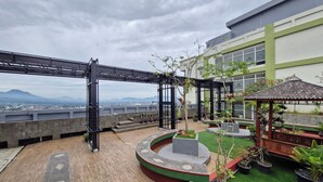 Een dakbostuin met een pergola, planten in potten, een prieel en uitzicht op verre bergen.