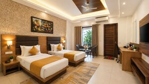 A hotel room with two beds, a desk, a TV, and a painting on the wall. - Hotel Grand Regency by JMD Group (New Delhi)