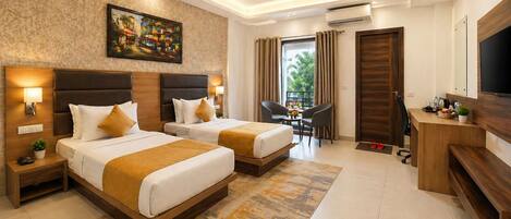 A hotel room with two beds, a desk, a TV, and a painting on the wall.
