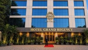 A modern hotel building with a large sign reading 'HOTEL GRAND REGENCY' and a logo above it. - Hotel Grand Regency by JMD Group (New Delhi)