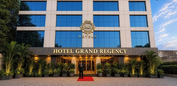 Un bâtiment d’hôtel moderne, avec une grande enseigne indiquant « HÔTEL GRAND REGENCY » et un logo au-dessus.