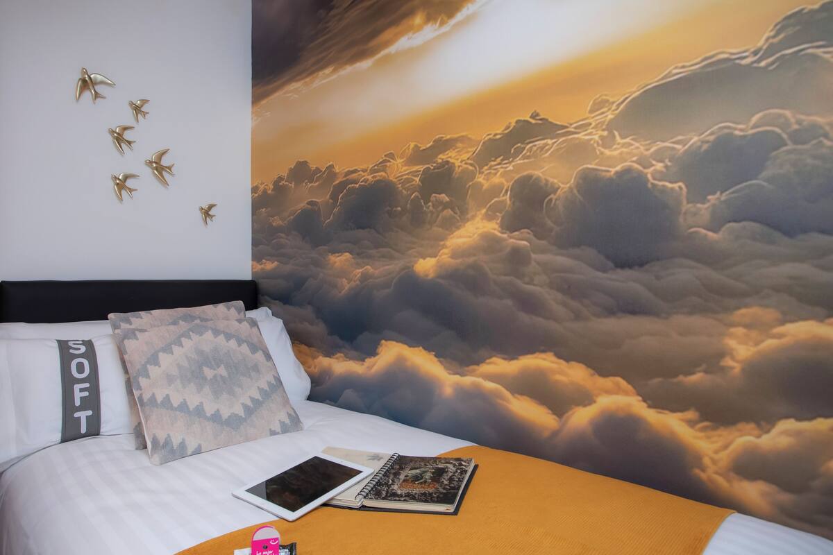 Une chambre à coucher avec un lit, des oreillers, un carnet et une tablette.