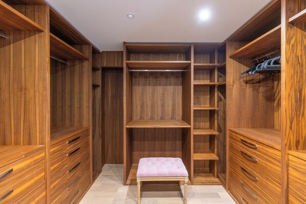 A walk-in closet with wooden shelving and drawers, a bench, and a hanging rack. - Apartment in Guildford with Parking (Guildford)