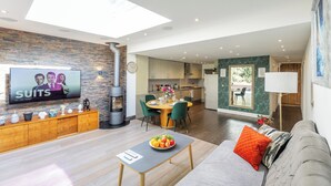A modern living room with a flat-screen TV, wooden console, and a dining area with a round table and chairs. - Apartment in Guildford with Parking (Guildford)
