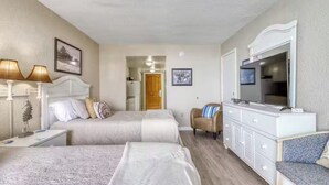 Une chambre d’hôtel avec deux lits, un téléviseur, une commode et une chaise.