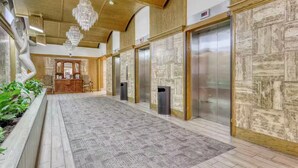 Un hall d’entrée spacieux, doté d’un tapis à motifs, d’un plafond en bois et d’un lustre.