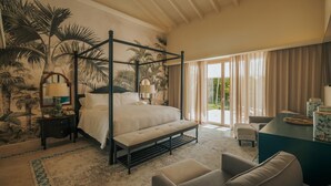 Una cama con dosel, un escritorio con silla, y vistas al exterior a través de amplios ventanales.
