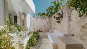 Un espacio exterior moderno con un muro de piedra, una bañera blanca y una zona de estar.