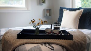 A neatly made bed with a black tray, a vase with flowers, and two mugs on a window sill. - View With a Room │ Mountain Home in Wine Country (Afton)