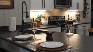 A kitchen counter with two plates, two wine glasses, and a salt and pepper shaker. - View With a Room │ Mountain Home in Wine Country (Afton)