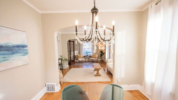 A spacious living area with a chandelier, a large painting, and a view into the dining area.