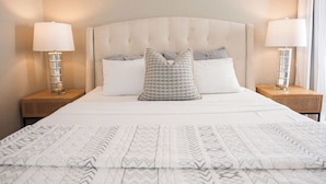 A neatly made bed with a patterned bedspread, two bedside lamps, and a tufted headboard.