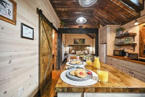 A wooden interior with a breakfast setup including waffles, fruit, and juice. - Cozy Couples Cabin/Private & Secluded/Hot Tub/Fire Pit/Hillside View (Broken Bow)