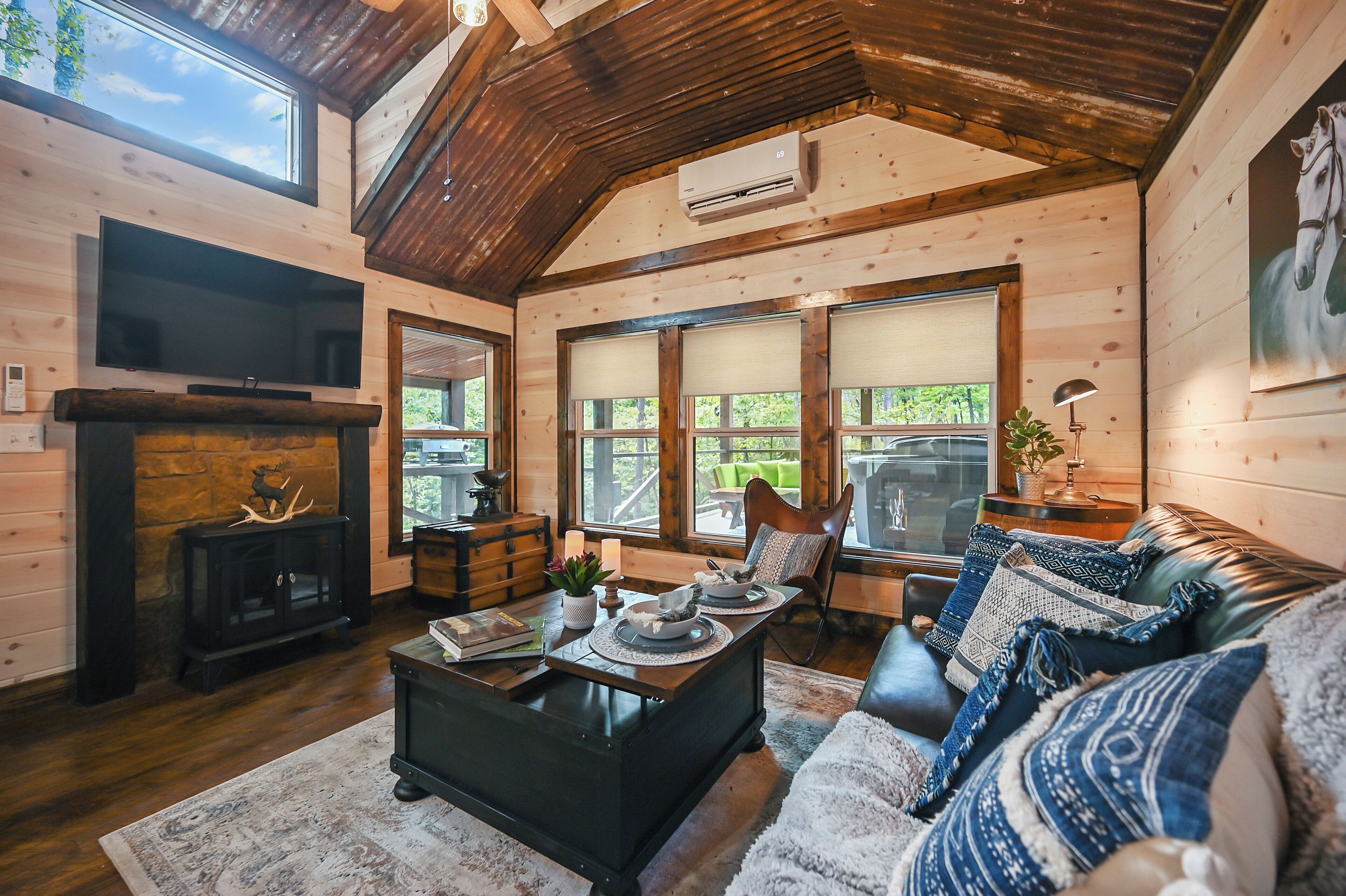 A cozy cabin interior with a fireplace, a television, and a comfortable seating area with a couch and a chair.
