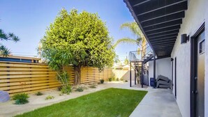 Un giardino sul retro con un albero, una recinzione in legno e un patio in cemento.