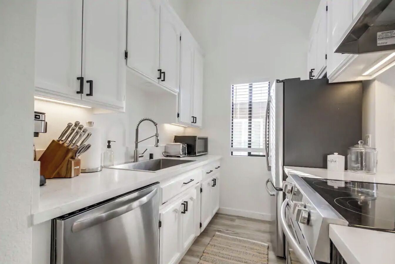 Una cocina moderna con armarios blancos, electrodomésticos de acero inoxidable y un salpicadero de azulejos.