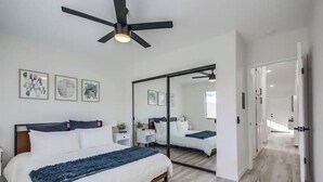 Camera da letto moderna con un letto, comodini, una ventola a soffitto e un ampio specchio.
