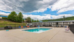 A hotel with a swimming pool, outdoor seating, and a parking lot.