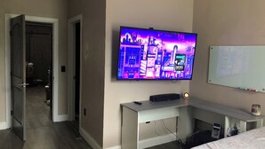 Une chambre avec un téléviseur fixé au mur, un bureau et un lit.