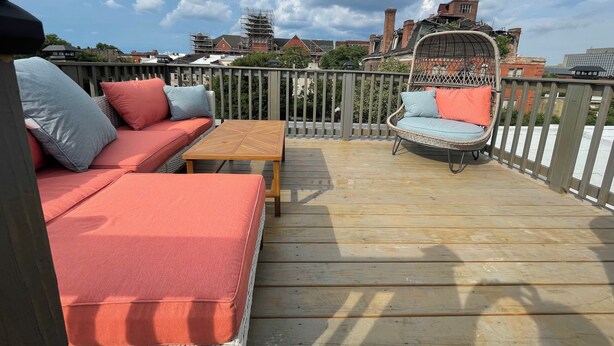 Une terrasse en bois avec un canapé, un fauteuil en osier et une table.