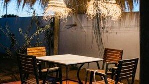 Un espace extérieur aménagé pour les repas, avec une table carrée et quatre chaises.