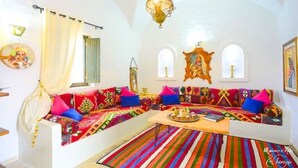 Un salon chaleureux et accueillant, avec un canapé aux couleurs vives, une table basse en bois et un tapis à rayures.