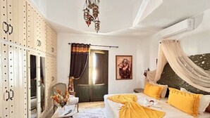 Une chambre à coucher avec un lit, un bureau, une chaise, une armoire et une porte.