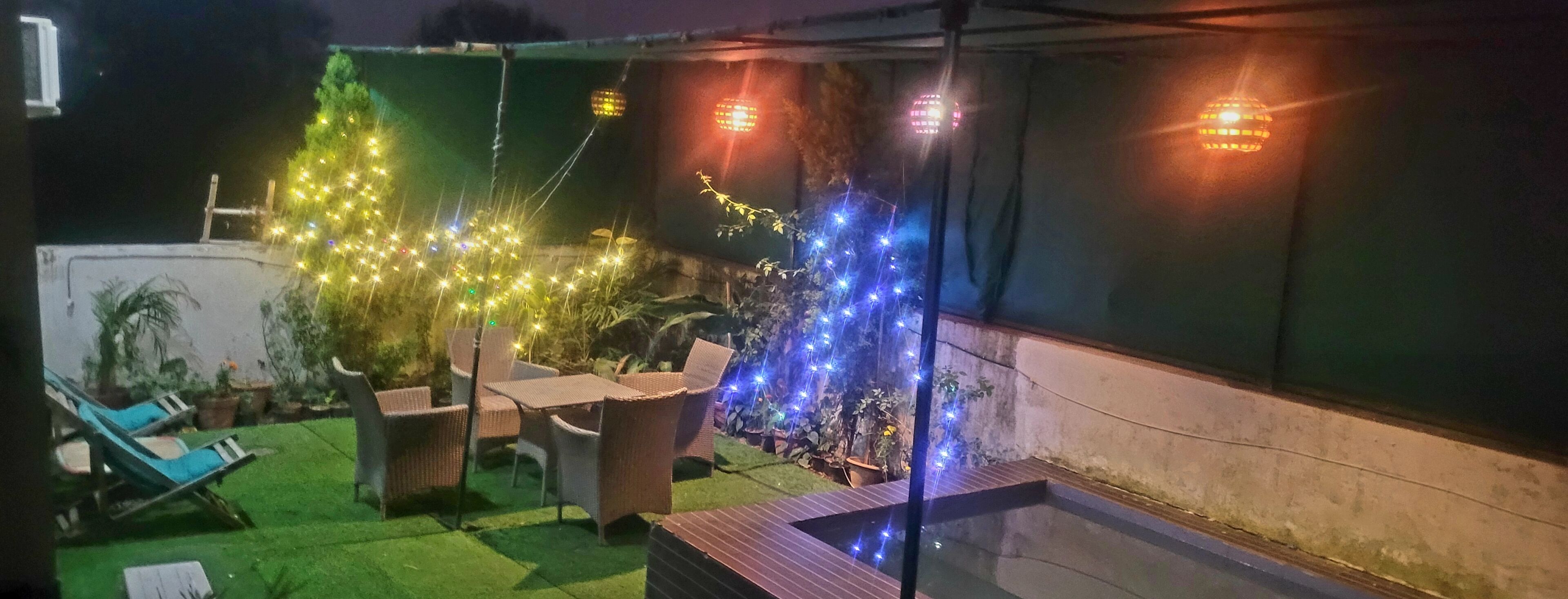 Un espace patio aménagé avec du mobilier d’extérieur et des guirlandes lumineuses.