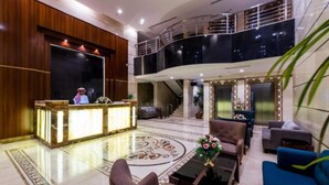 A spacious lobby with a reception desk, seating area, and a staircase leading to an upper level.
