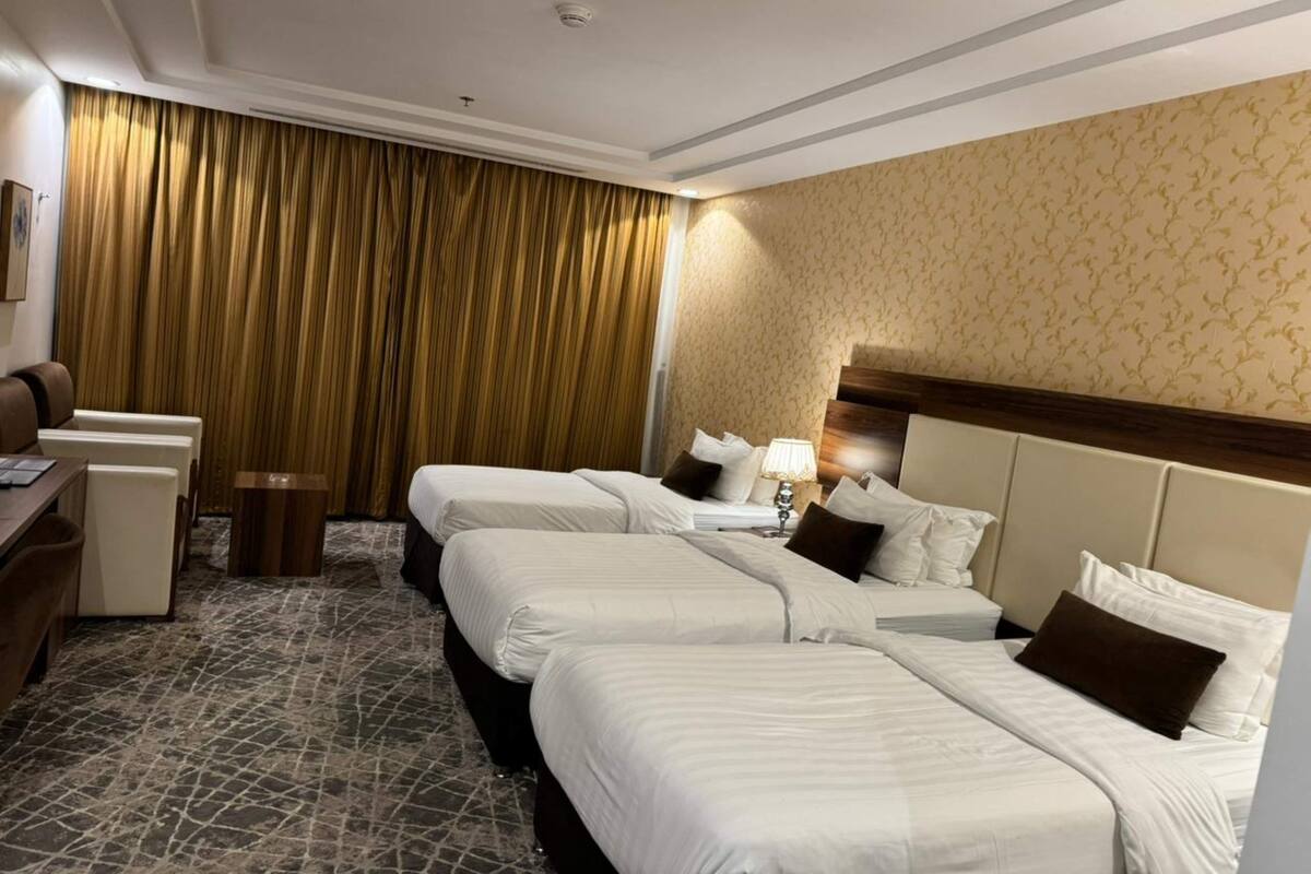 Een hotelkamer met drie bedden, een bureau en een stoel.