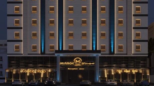 A multi-story hotel with a modern facade, featuring illuminated windows and a reception area.