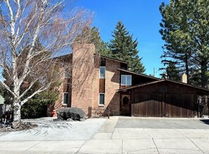 A two-story building with a brick facade, a wooden garage, and a clear sky. - Beautiful & Spacious 7-Beds by 𝐁𝐘𝐔𝐈 (Rexburg)