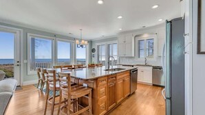 A spacious kitchen with a large island, wooden cabinets, and a view of the ocean. - 6br Oceanfront Cottage w/ awesome views and short walk to the boardwalk. (Carolina Beach)