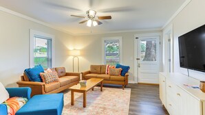 A living room with two sofas, a coffee table, and a TV on a stand. - Downtown Heflin Cottage w/ Deck & Fire Pit! (Heflin)