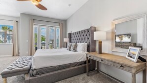 A hotel room with a bed, a desk, a chair, a ceiling fan, a window, and a TV. - Patriot's Peaceful Retreat: Private Pool, Free Water Park, Near Disney (Kissimmee)
