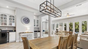 A spacious kitchen with white cabinetry, a wooden dining table, and a large clock on the wall. - Patriot's Peaceful Retreat: Private Pool, Free Water Park, Near Disney (Kissimmee)