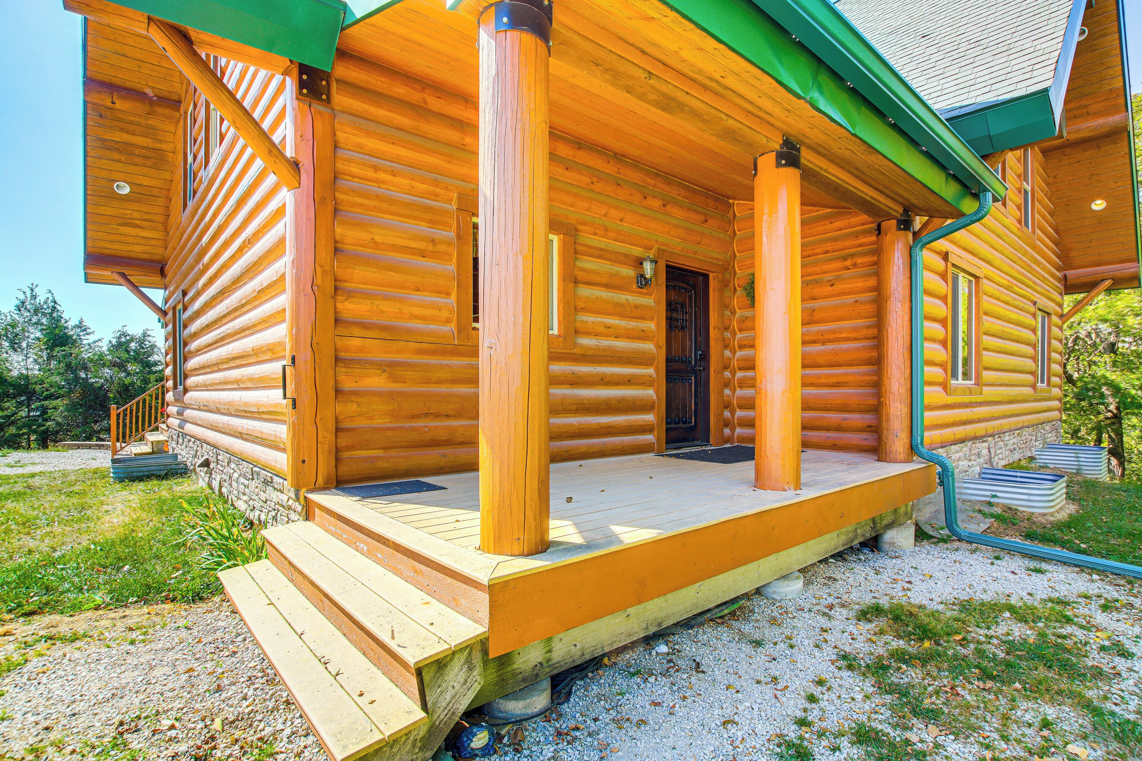 A log cabin with a porch, steps, and a door.