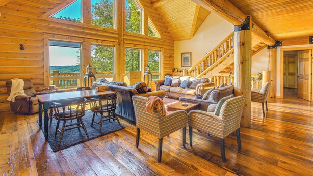 Ein geräumiger Blockhausausschnitt mit Essbereich, einer großen Sofaecke und einer Treppe, die zu einer oberen Ebene führt.