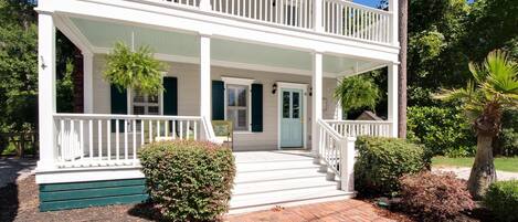 A two-story house with a porch, a front door, and a small garden area.