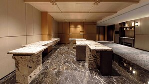 Een moderne keuken met marmeren aanrechtbladen en houten keukenkastjes.