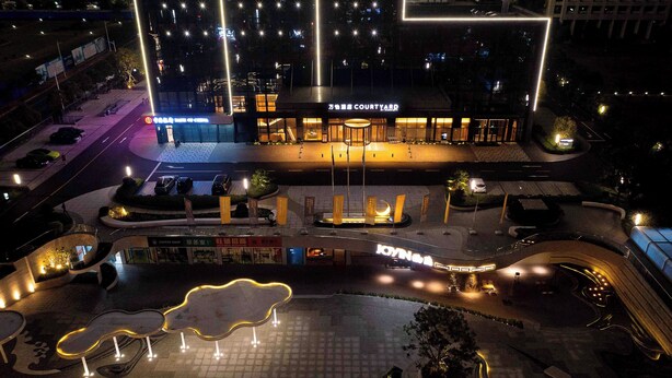 Een goed verlicht stadsplein met een modern gebouw, voorzien van een grote ingang en borden.