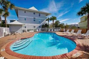 Relax by the pool surrounded by lounge chairs and a wooden deck.
