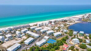Stunning coastal resort with a mix of single-story and multi-story buildings, adjacent to a sandy beach and a body of water.