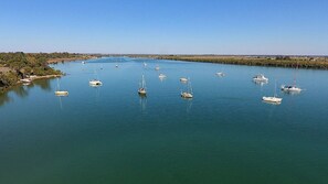 Enjoy serene waterfront views and tranquil sailboats in a picturesque marina surrounded by lush vegetation.