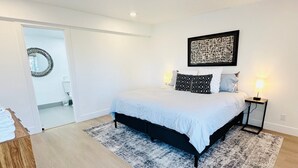 A modern bedroom with a bed, a rug, and a wall art piece. - Mountain Views Condo | Community Pool & Hot Tub (Zephyr Cove)