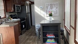 A modern kitchen with wooden cabinets, stainless steel appliances, and a herringbone-patterned floor. - Great Getaway in adorable Cherokee Landing at Indian Lake with AC, WiFi (Lakeview)
