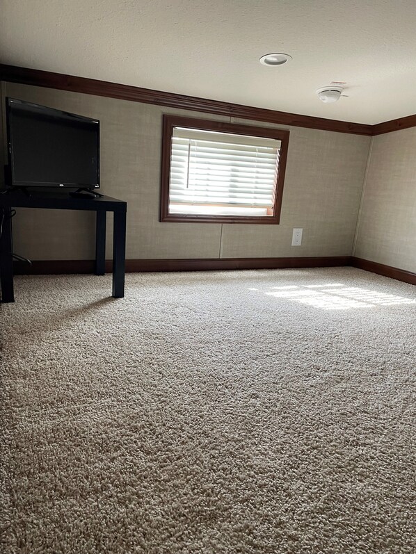 A room with a large window, carpeted floor, and a television on a stand. - Great Getaway in adorable Cherokee Landing at Indian Lake with AC, WiFi (Lakeview)