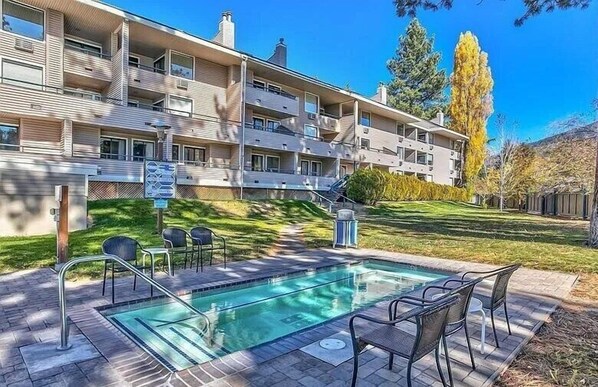 Un immeuble d’appartements moderne doté d’une piscine, d’un espace extérieur aménagé et d’une pelouse bien entretenue.