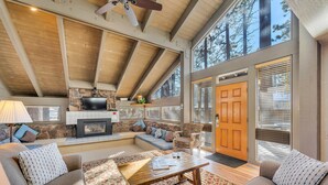 A spacious living room with a fireplace, comfortable seating, and large windows offering a view of the outdoors. - Steps to Beach | Deck | Community Pool & More (South Lake Tahoe)