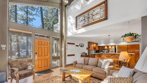 A spacious living area with a sofa, coffee table, and a view of the outdoors through large windows. - Steps to Beach | Deck | Community Pool & More (South Lake Tahoe)